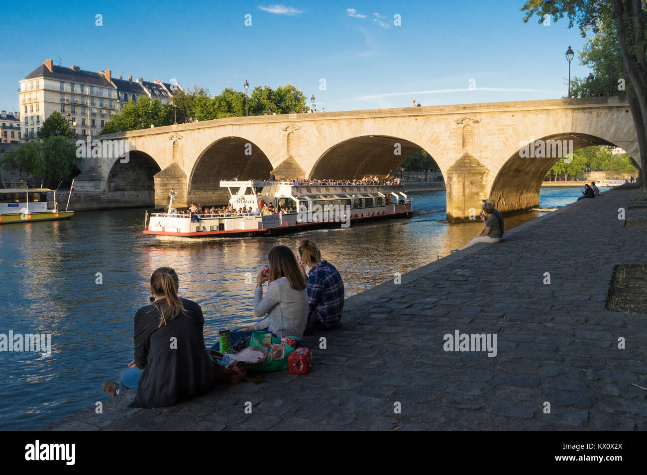 Francia, Parigi (75), Donna fare picnic sul Quai de Bourbon con il Pont Marie dietro Foto Stock