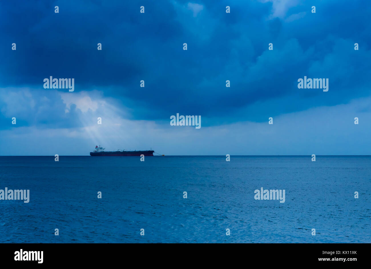 Sole brillante raggi provenienti attraverso dense nubi su una solitaria nave in mare Foto Stock
