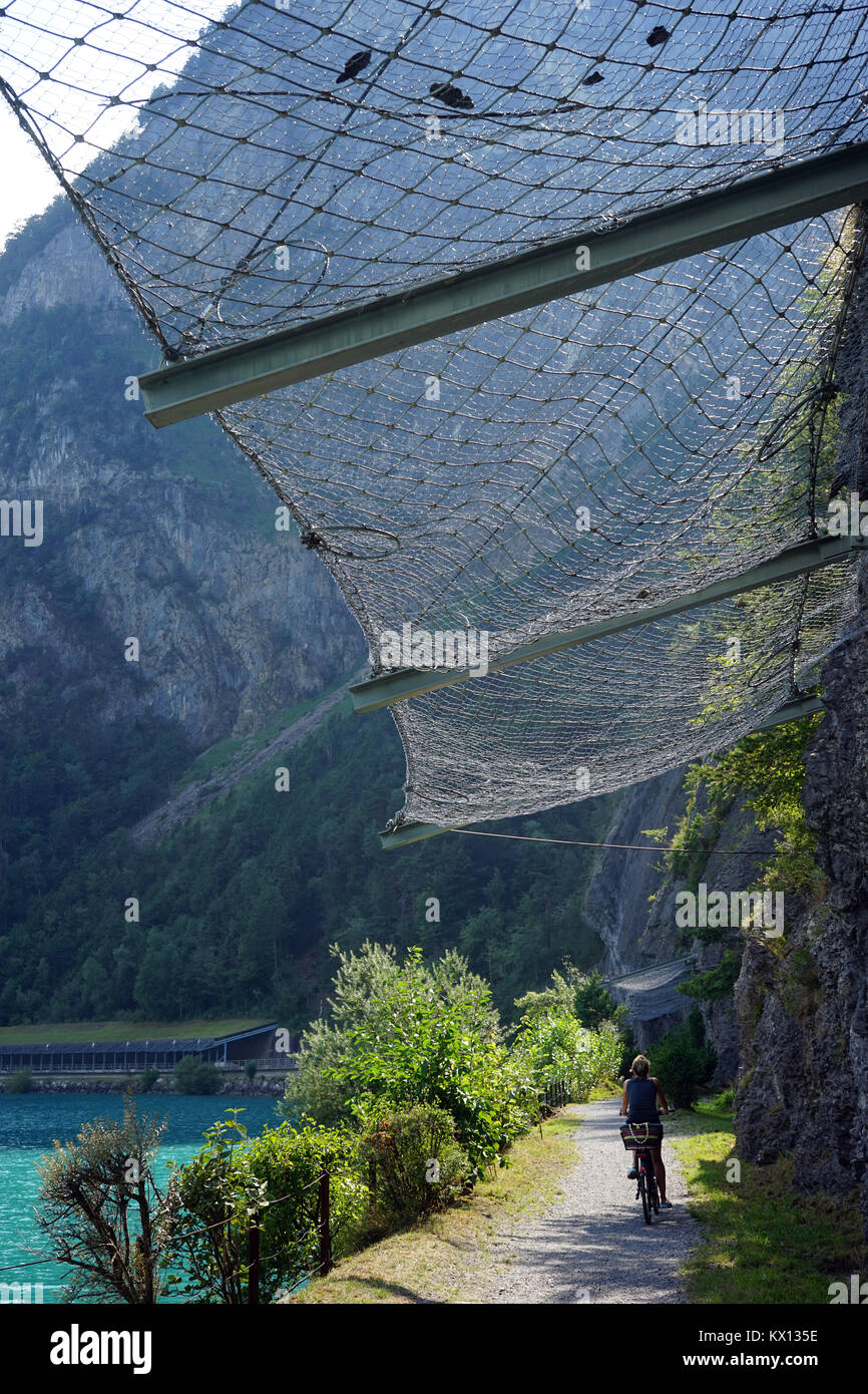 BAUEN, Svizzera - circa agosto 2015 Donna sulla bicicletta nei pressi di roccia e il lago di Lucerna Foto Stock