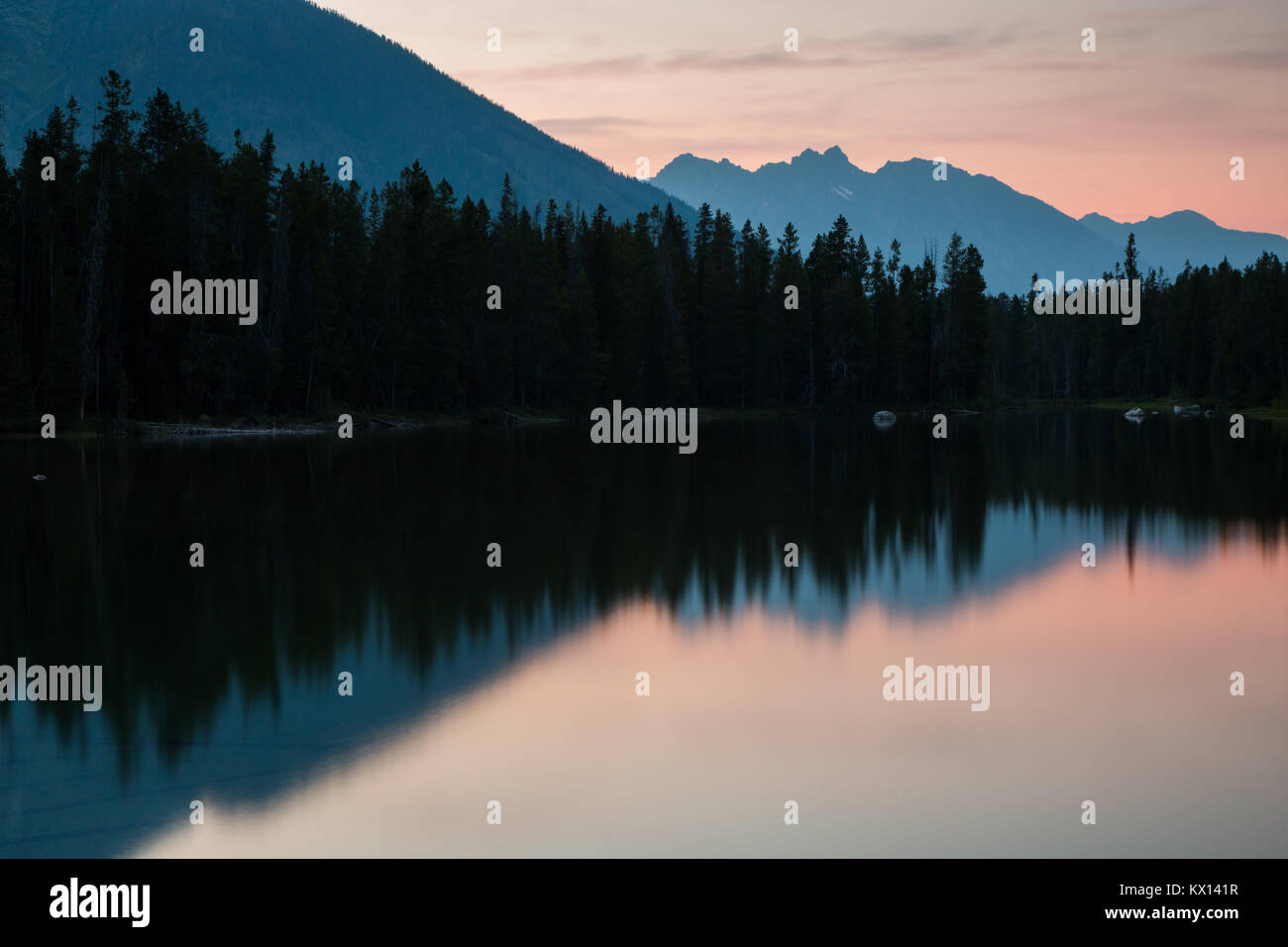 Un tramonto riempito di incendio di foresta riflettente di fumo nelle acque del lago di stringa. Il Parco Nazionale del Grand Teton, Wyoming Foto Stock