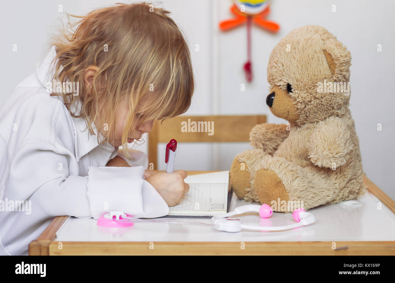Bambina gioca un medico con il suo orsacchiotto Foto Stock