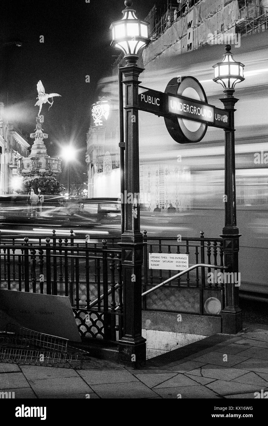 Pubblico metropolitana entrata a Piccadilly Circus con Londra Trasporto bus passante e la statua di Eros, di notte, Londra, Inghilterra, degli anni ottanta Foto Stock