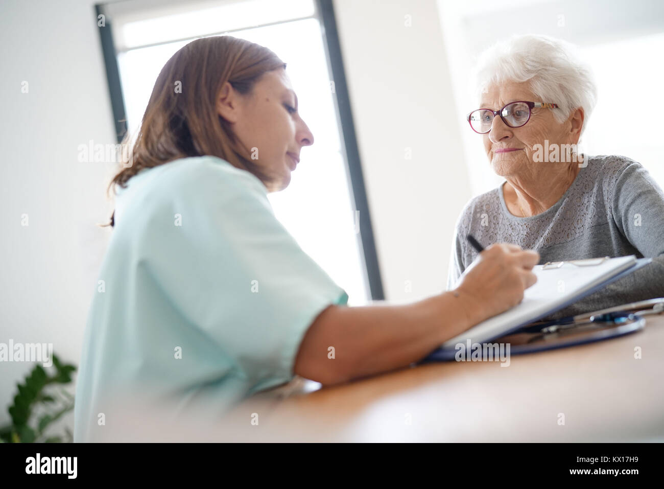 L'infermiera dando la prescrizione di donna anziana Foto Stock