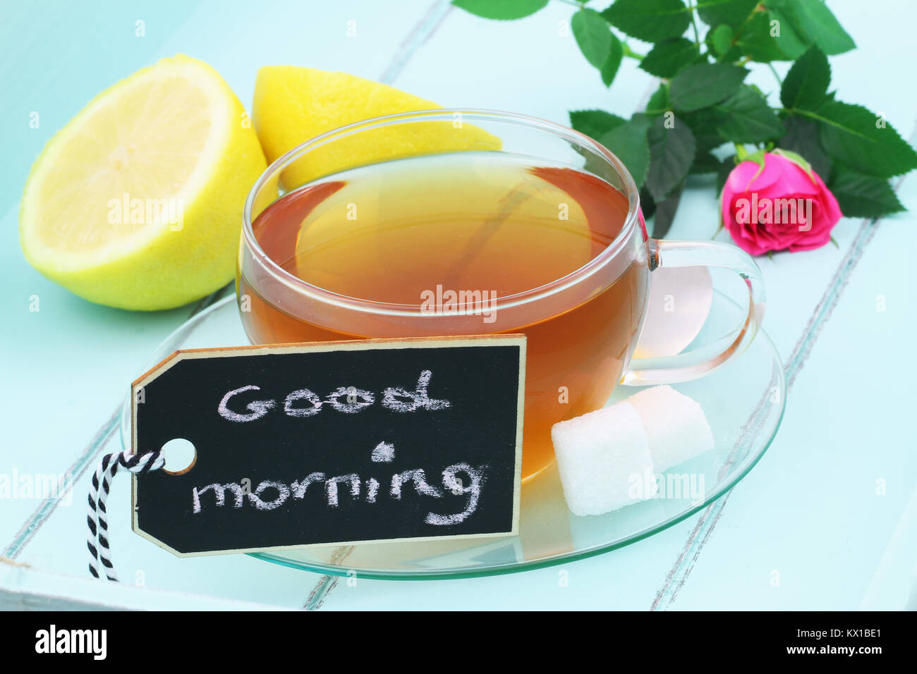 Buona mattina card con tazza di tè nero e rosa rosa su legno verde Foto Stock