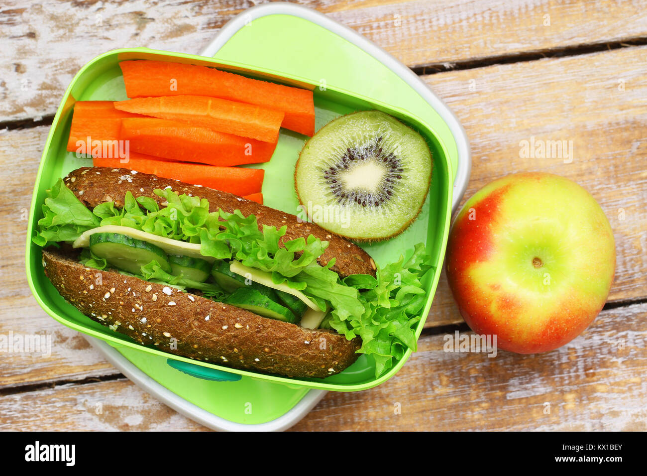 Pranzo sano scatola contenente formaggio marrone sandwich, croccante carote, kiwi e Apple Foto Stock