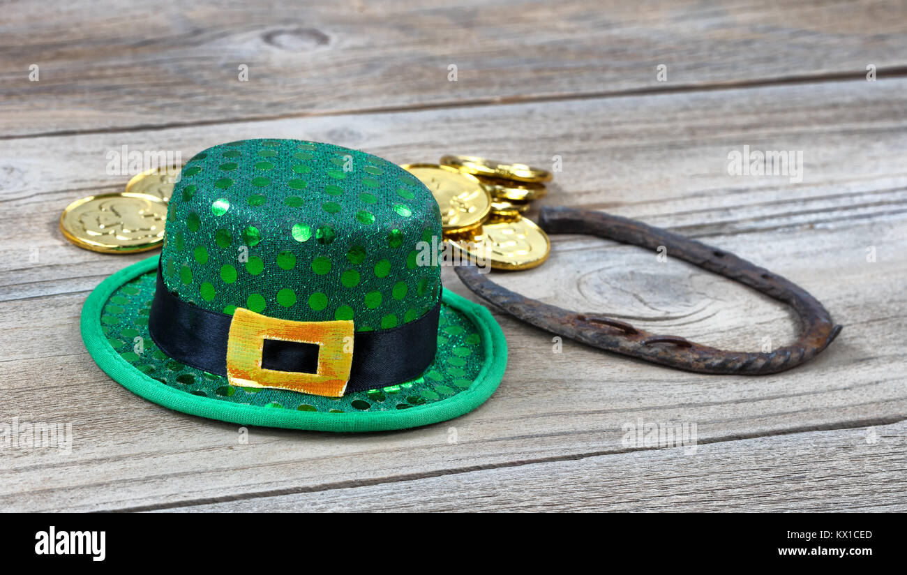 Lucky Green hat, a ferro di cavallo e monete d'oro per St Patrick su rustiche tavole in legno in vista ravvicinata Foto Stock