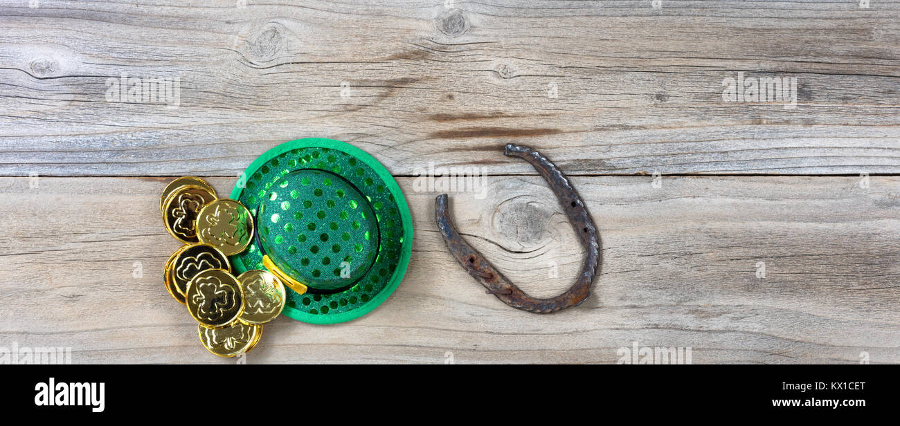 Lucky Green hat, a ferro di cavallo e monete d'oro per St Patrick su rustiche tavole in legno in vista aerea Foto Stock