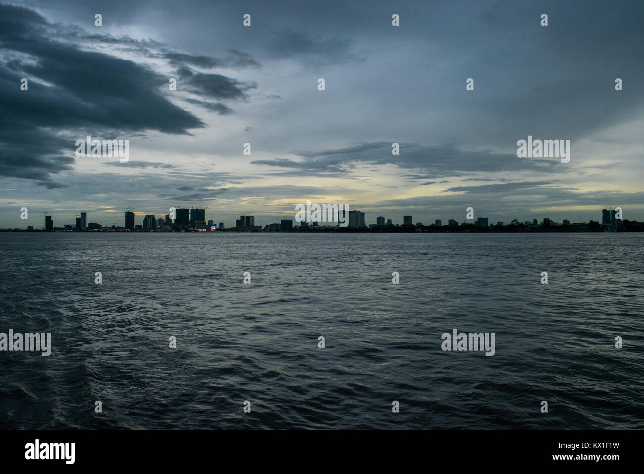 Phnom Penh tramonto tramonto visto dal Mekong e il Tonle Sap fiumi, emergono con sky raschiatori. Stagione dei monsoni e la pioggia nuvole avvicinando alla città Foto Stock