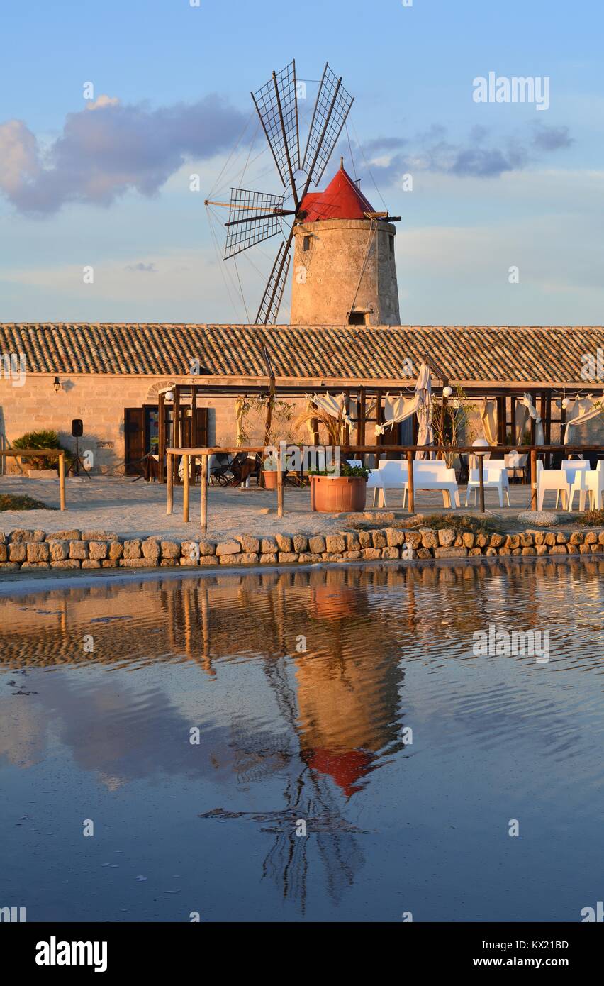 Uno dei tradizionali mulini a vento nelle saline di Trapani, Sicilia (Italia) riflesso in un bacino di sale. Foto Stock