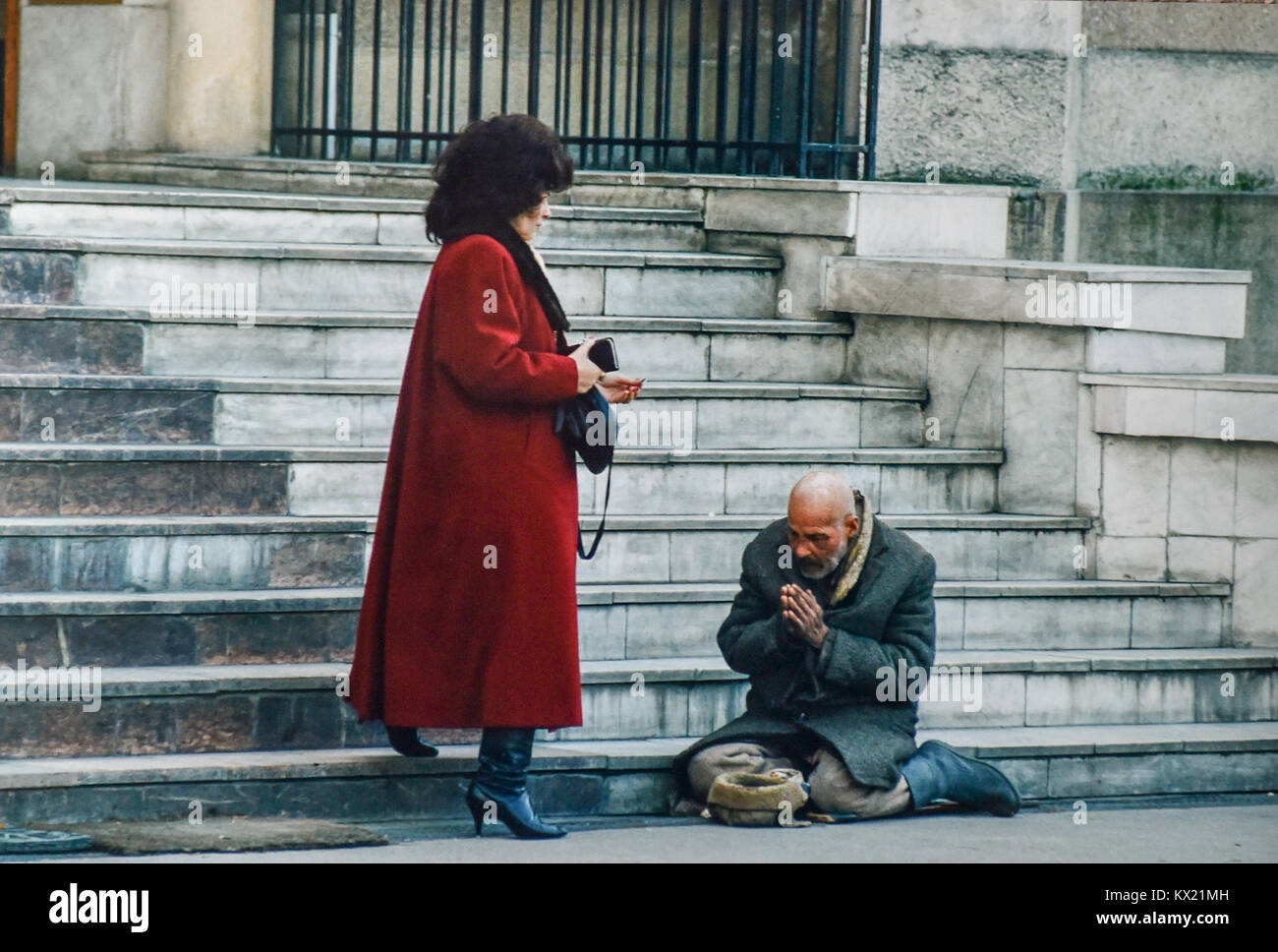 La Romania 1994 - contrasto tra ricchi e poveri dopo la rivoluzione come una donna facoltosa passa un mendicante per le strade di Timisoara Foto Stock
