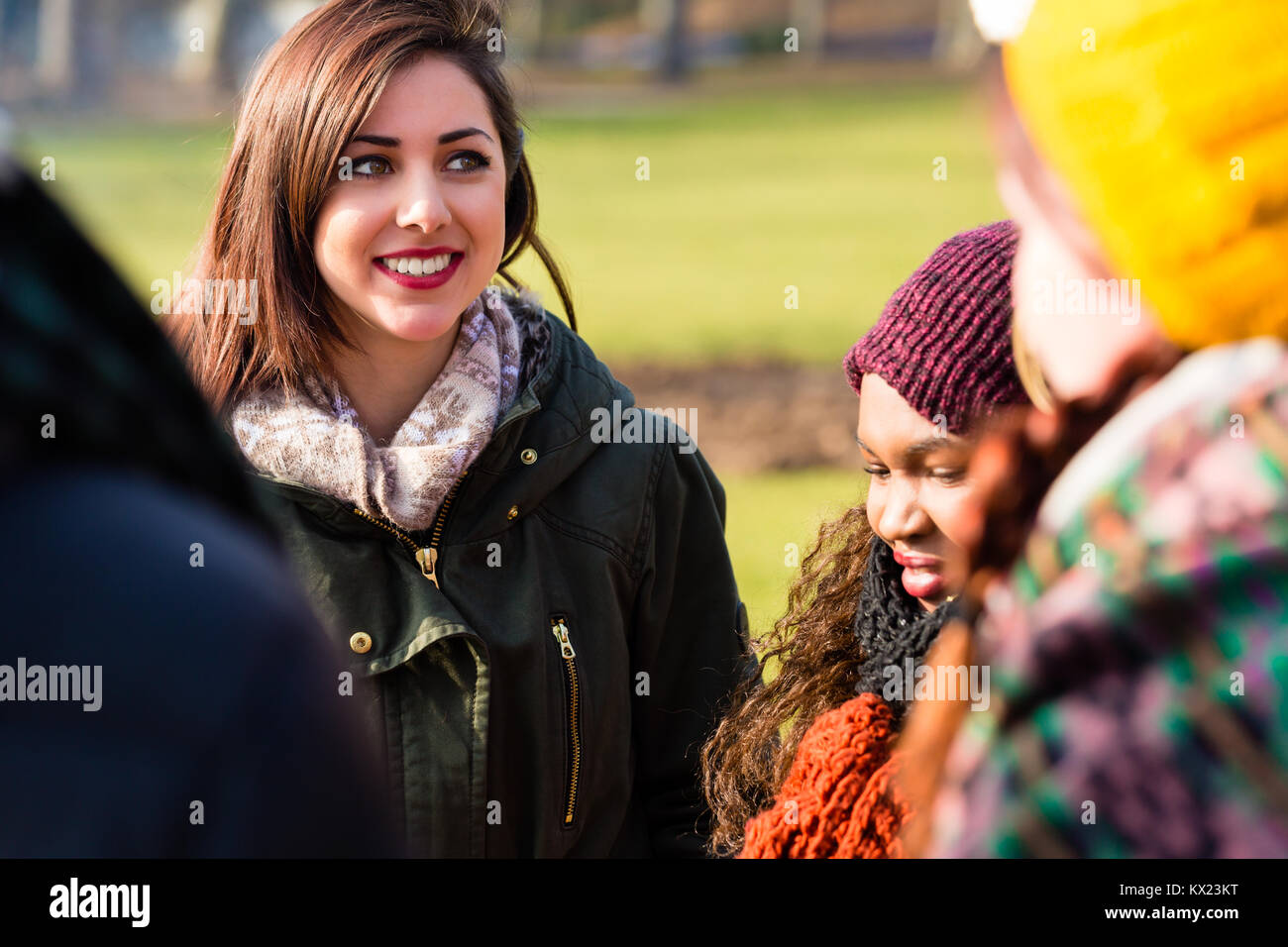 Sicuro di sé giovane donna circondata da amici all'aperto Foto Stock