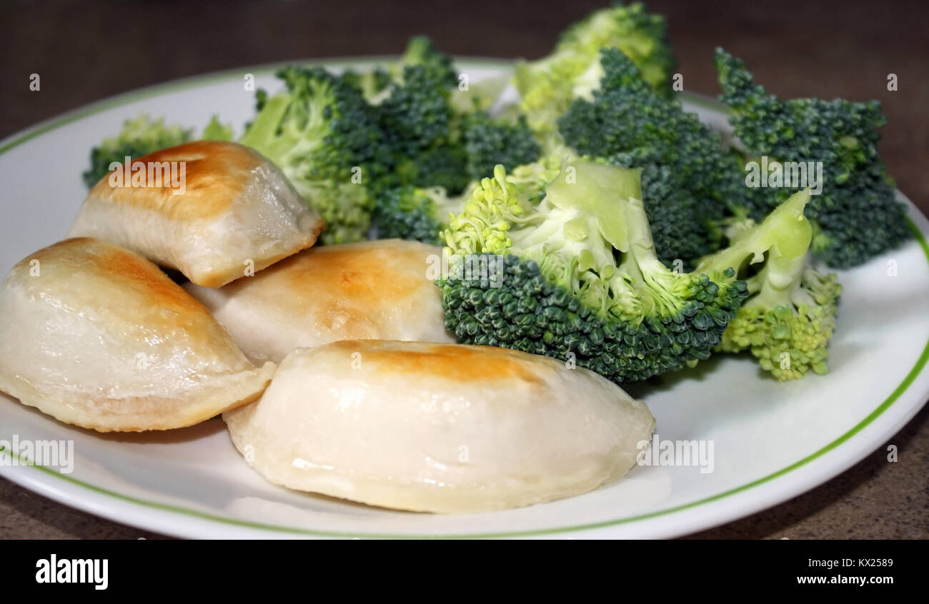 Fritti Perogies farcite con un lato di broccoli freschi Foto Stock