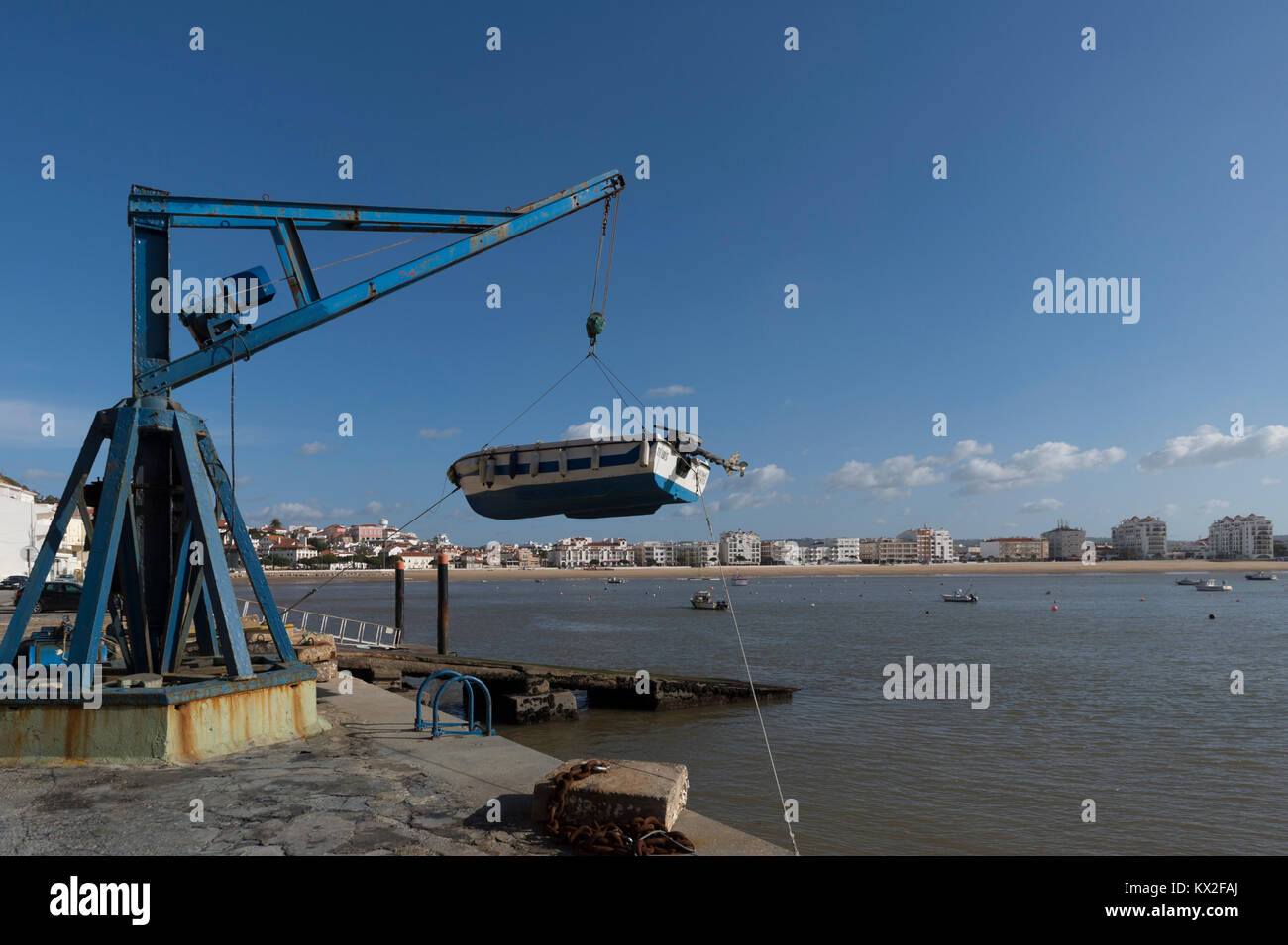 Piccola barca da pesca che viene sollevato al di fuori del porto tramite paranco della gru in São Martinho do Porto, Portogallo. Foto Stock