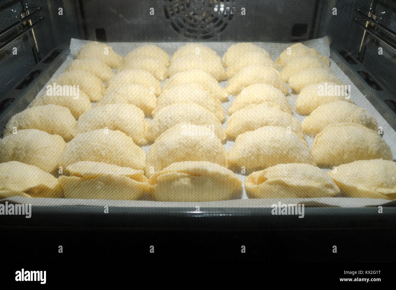 Set di dolci fatti in casa il lievito brioche coperta di cristalli di zucchero e riempito con le mele durante la cottura all'interno di home forno del pane. Foto Stock