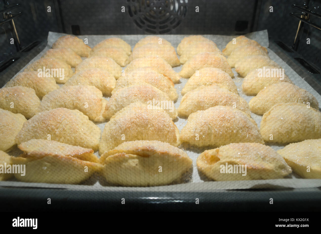 Set di dolci fatti in casa il lievito brioche coperta di cristalli di zucchero e riempito con le mele durante la cottura all'interno di home forno del pane. Foto Stock