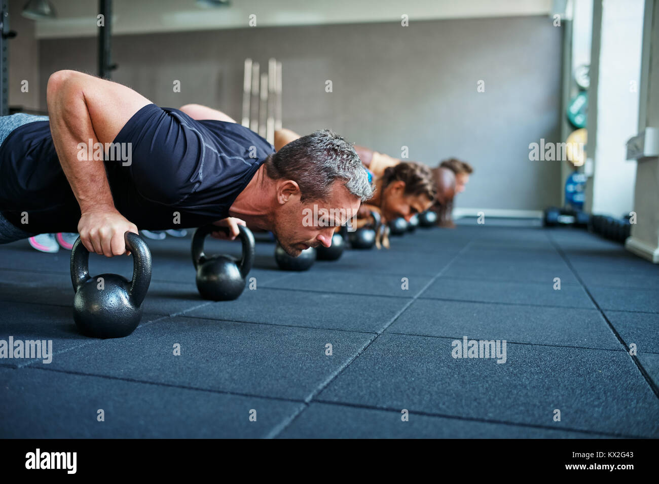 Concentrati gruppo di persone che lavorano insieme sul pavimento con pesi durante un health club class Foto Stock