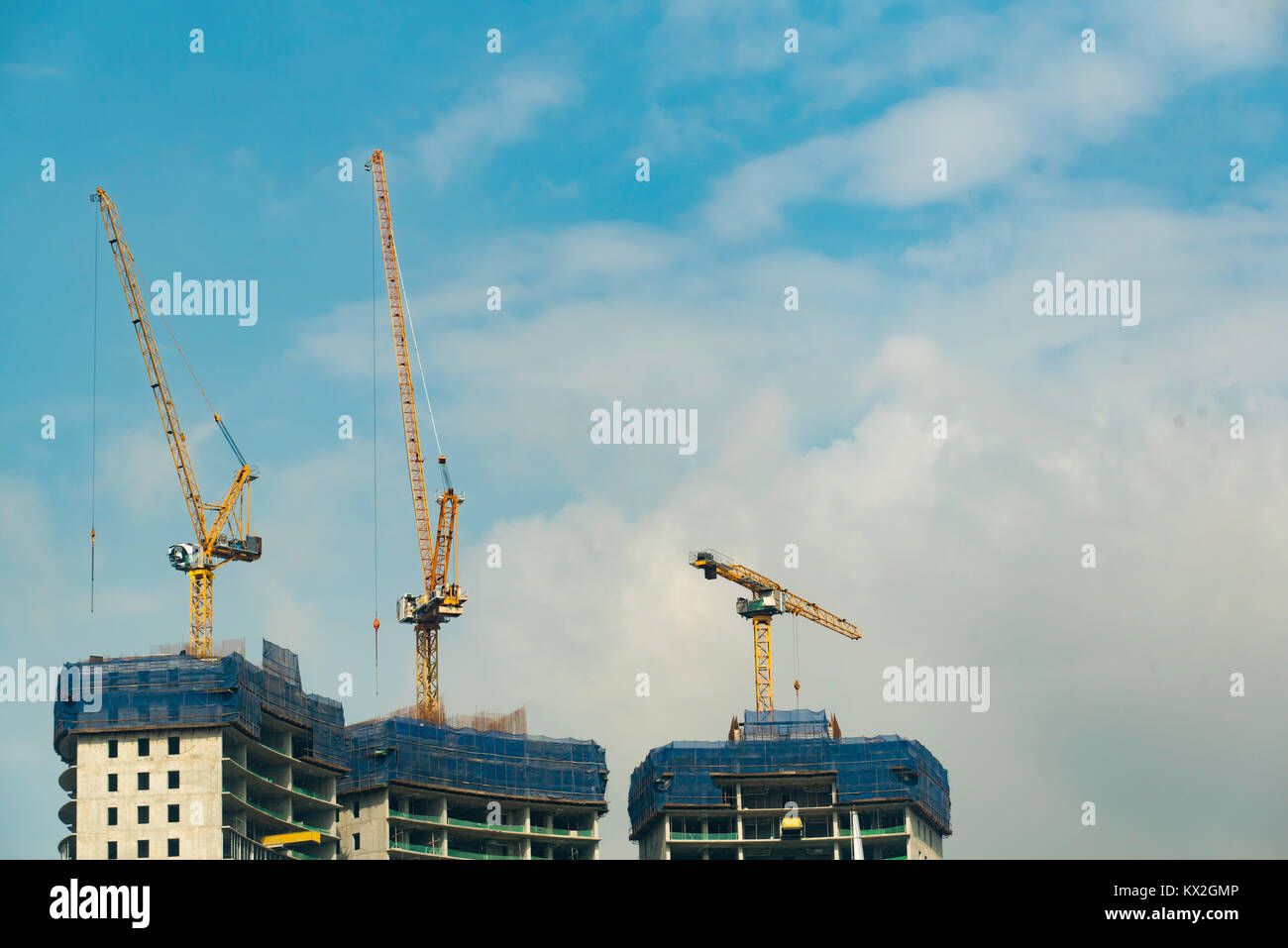 Gru sedersi nella parte superiore di tre torri costruite in Kualar Lumpur in Malesia Foto Stock