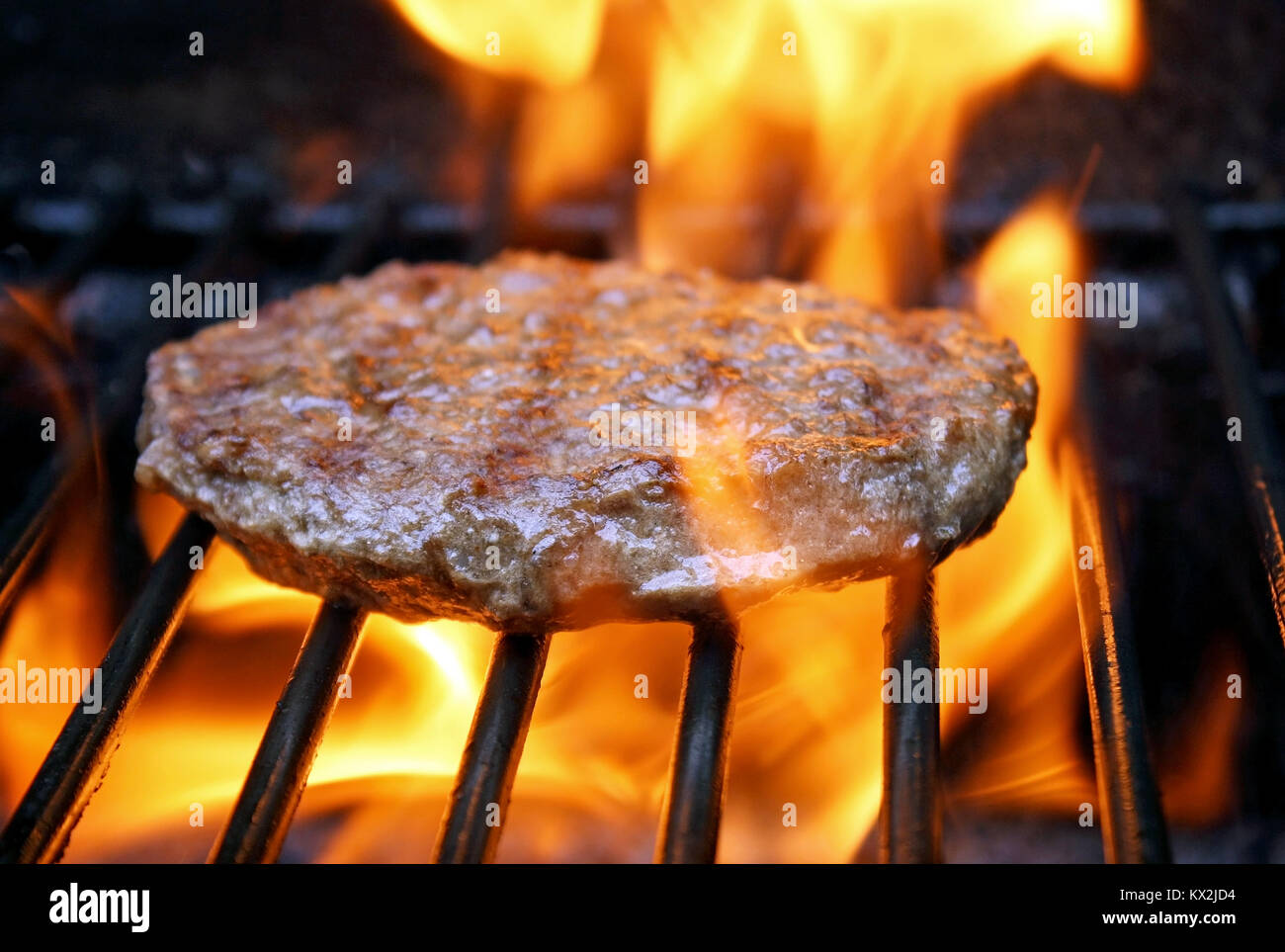 Succose carni bovine burger sfrigolante su caldo fiamme sul barbecue Foto Stock