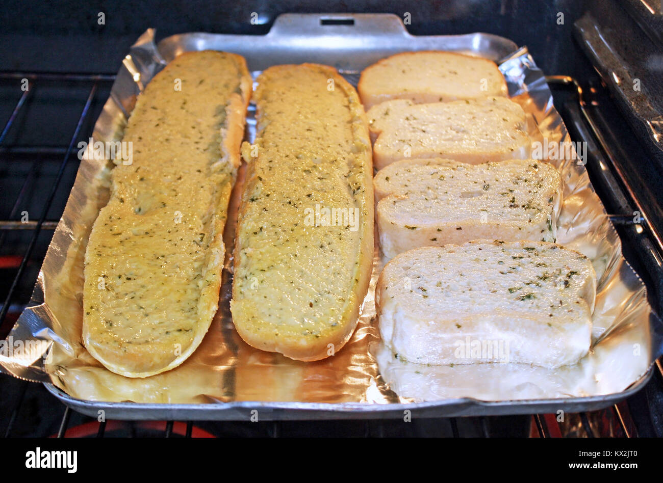 Deliziosa burrosa aglio pane cottura su un foglio di alluminio all'interno del forno Foto Stock