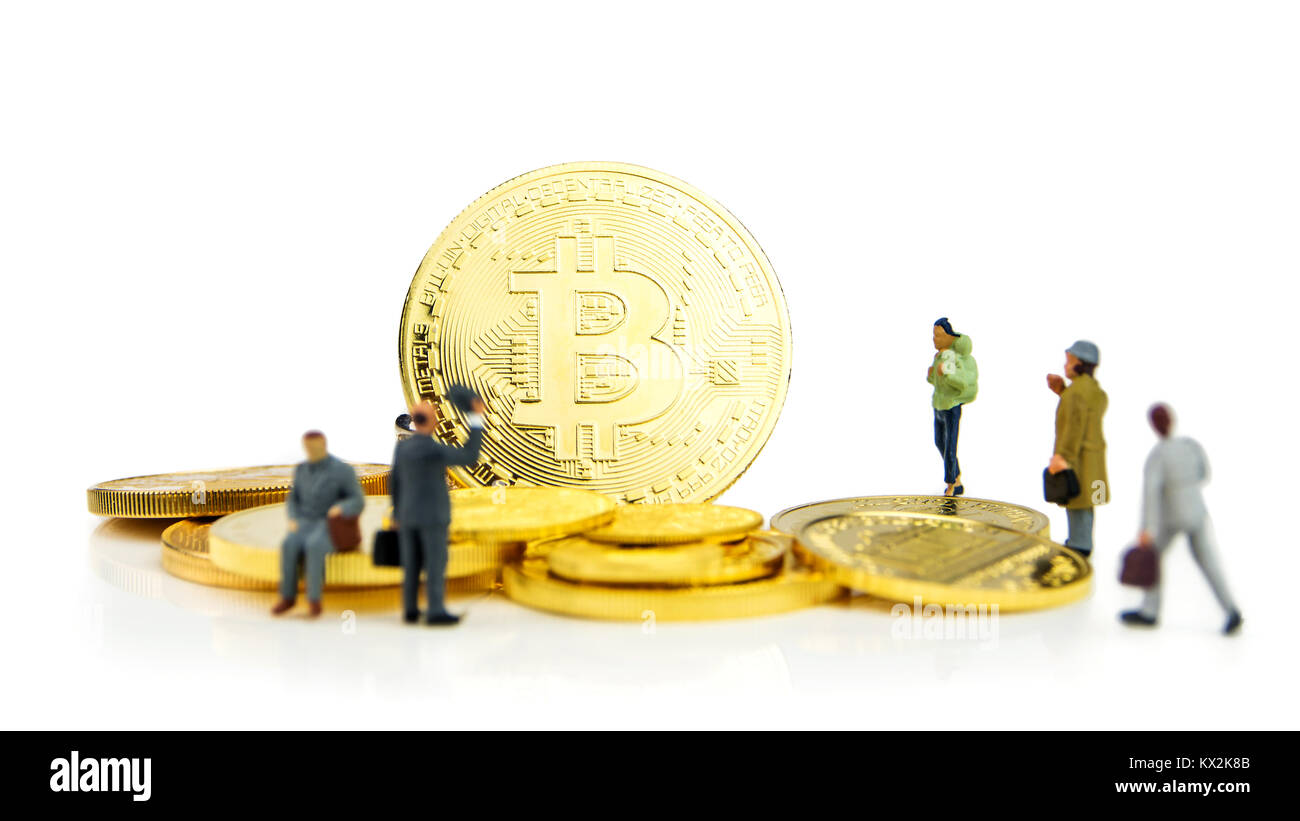 Primo piano della golden bitcoin moneta su sfondo bianco con molte monete d oro a fondo e statuine in miniatura in piedi intorno Foto Stock