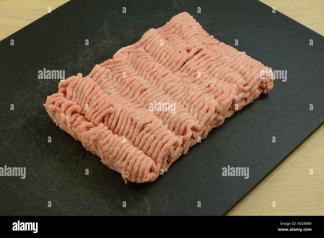 Terra cruda di carne di tacchino su nero tagliere sul tavolo di legno Foto Stock
