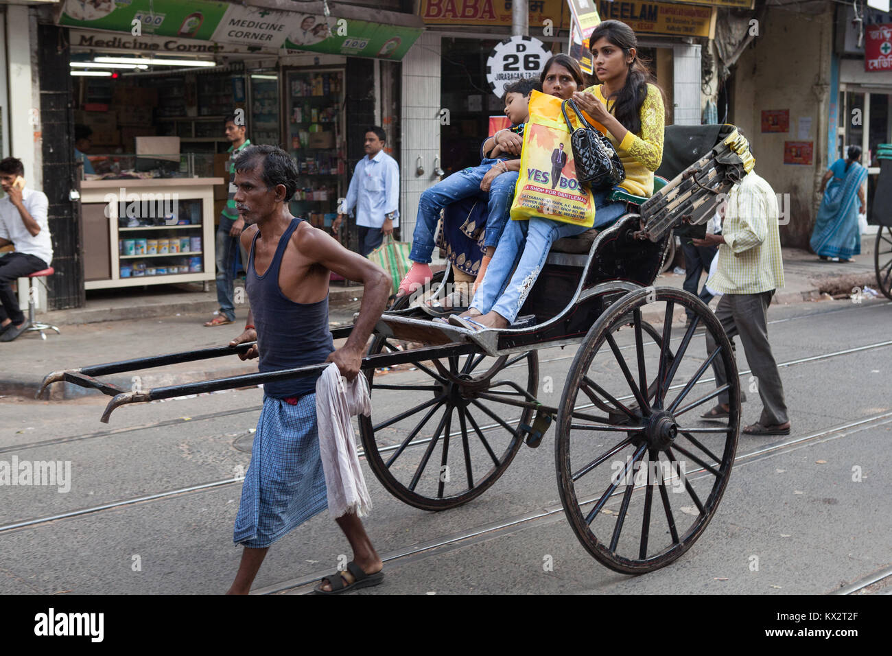 Un rickshaw driver porta i passeggeri attraverso le strade di Calcutta, in India Foto Stock