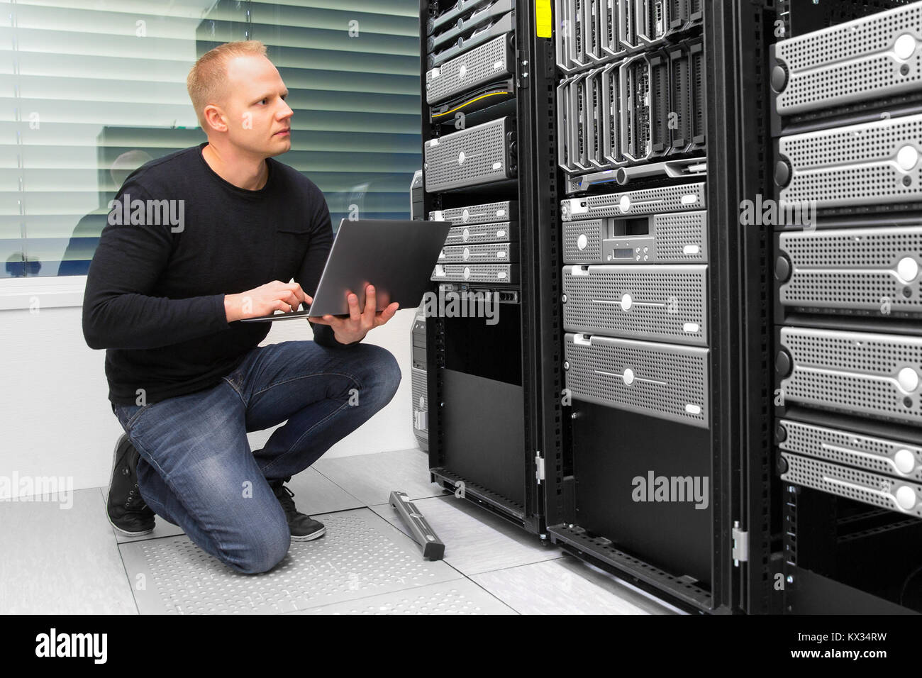 Consulente utilizzando computer portatile mentre il monitoraggio dei server nel data center Foto Stock