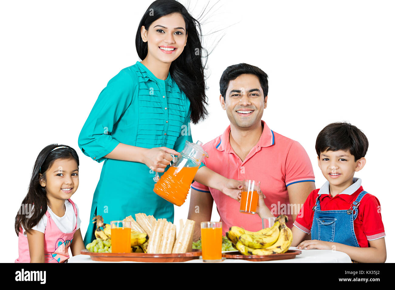 La famiglia felice i genitori e i bambini colazione mattutina madre che serve succhi di frutta Foto Stock