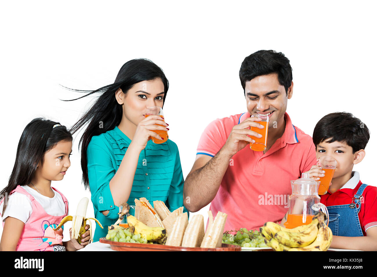 La famiglia felice i genitori e i bambini a bere succo di frutta sala prima colazione al mattino Foto Stock