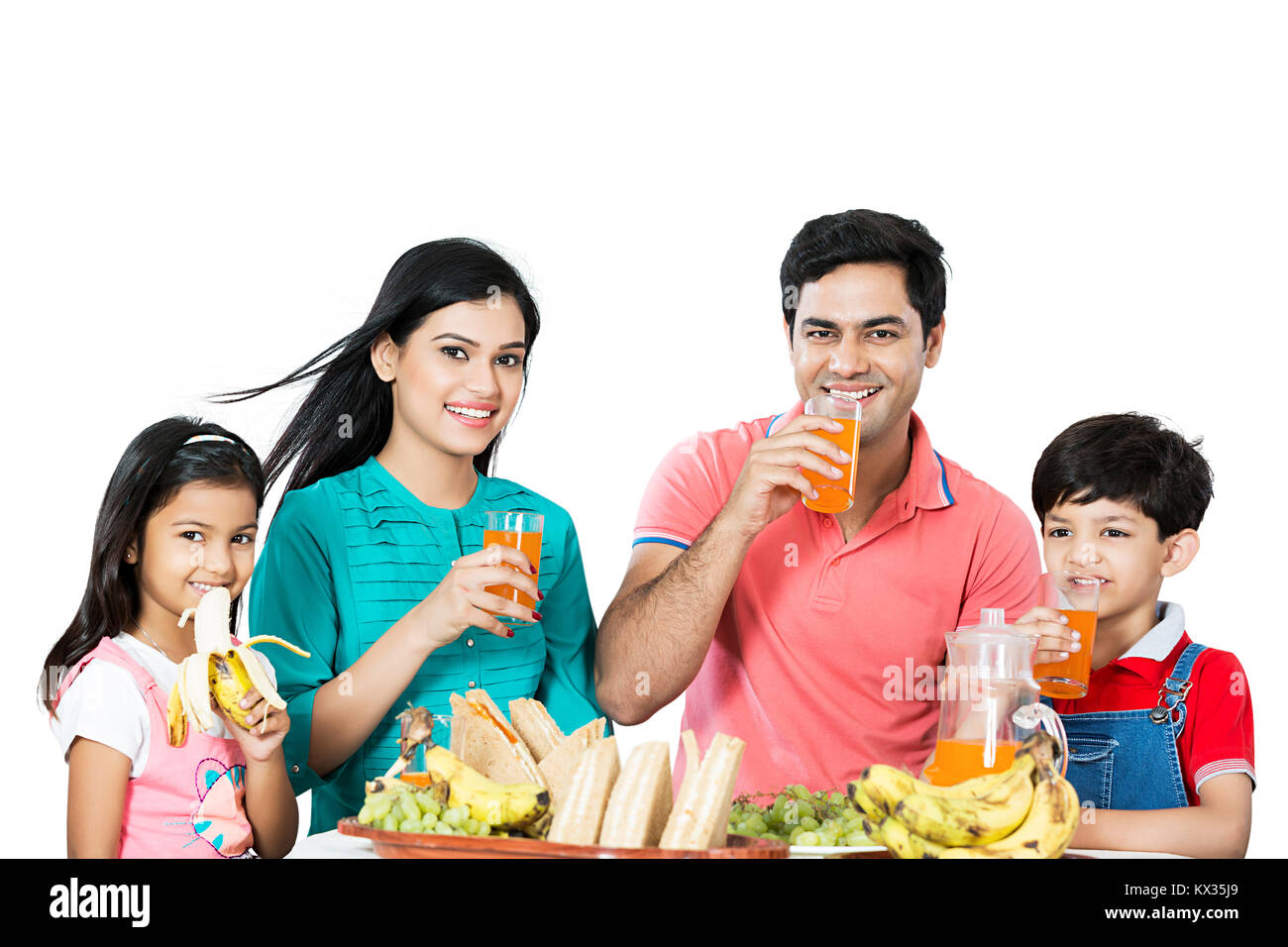 La famiglia felice i genitori e i bambini a bere il succo d'Arancia prima colazione al mattino Foto Stock