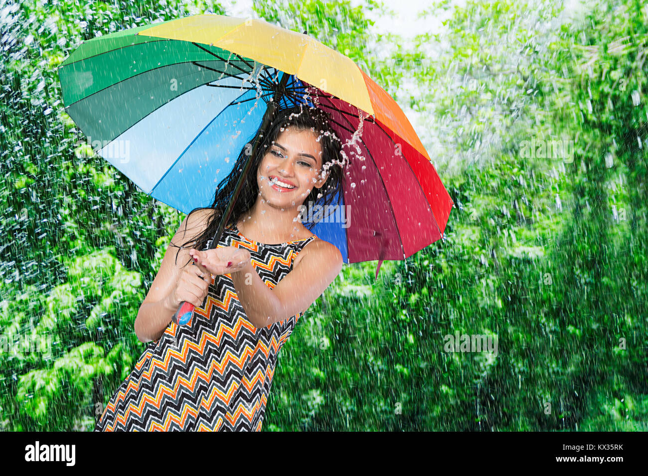 Felice bella giovane donna godendo della pioggia di estate nel parco Foto Stock