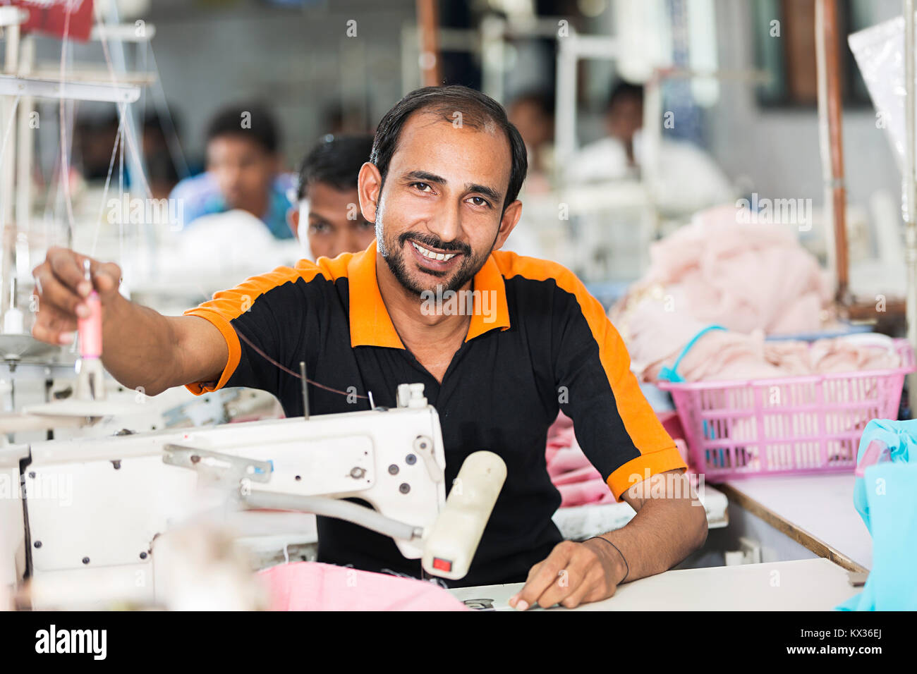 Sorridente 1 uomo lavoratore lavoro sarto macchina da cucire in officina Foto Stock