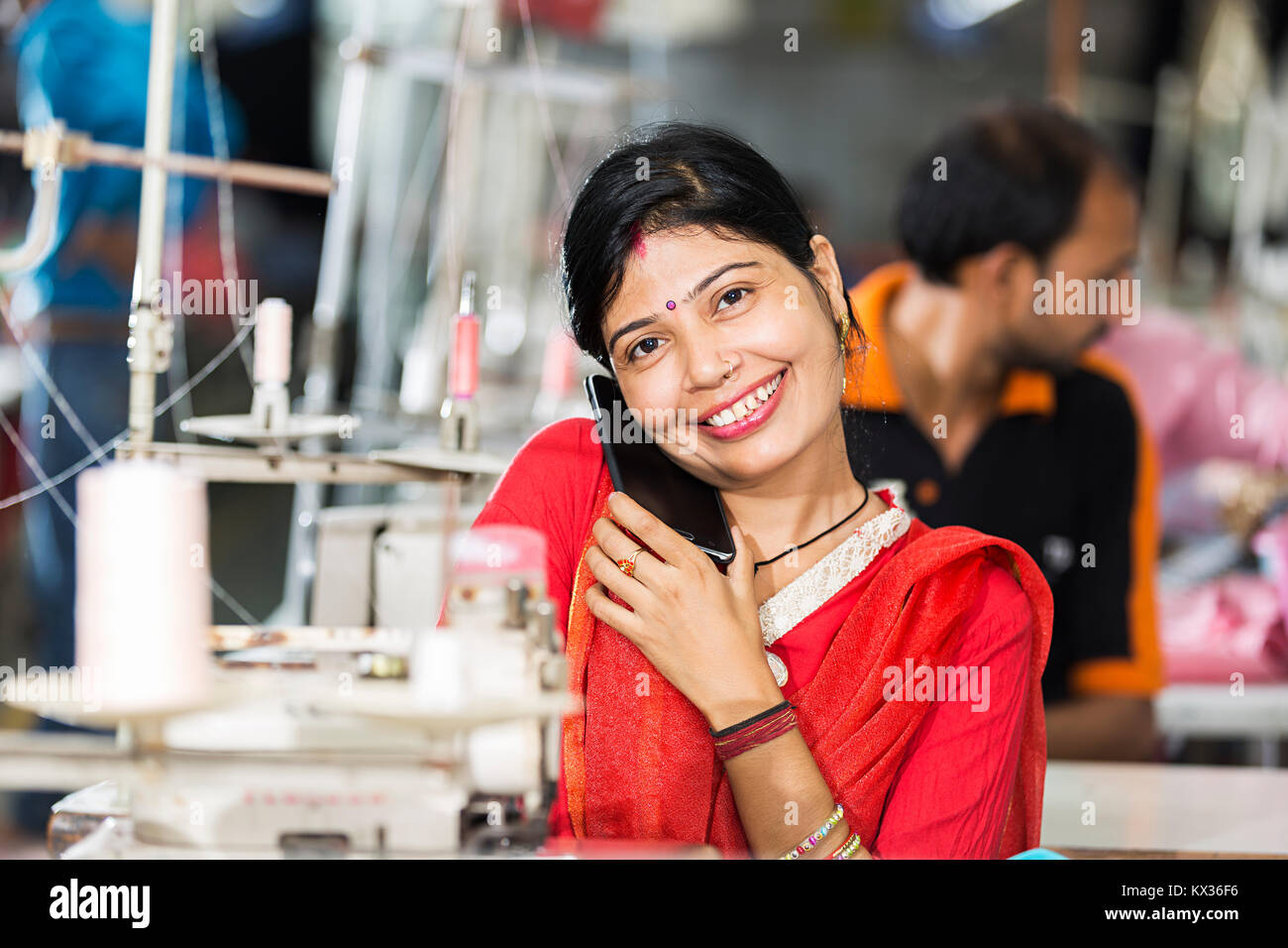 Una signora lavoratore su misura abiti da lavoro e parlando Mobile-Phone indumento-factory Foto Stock