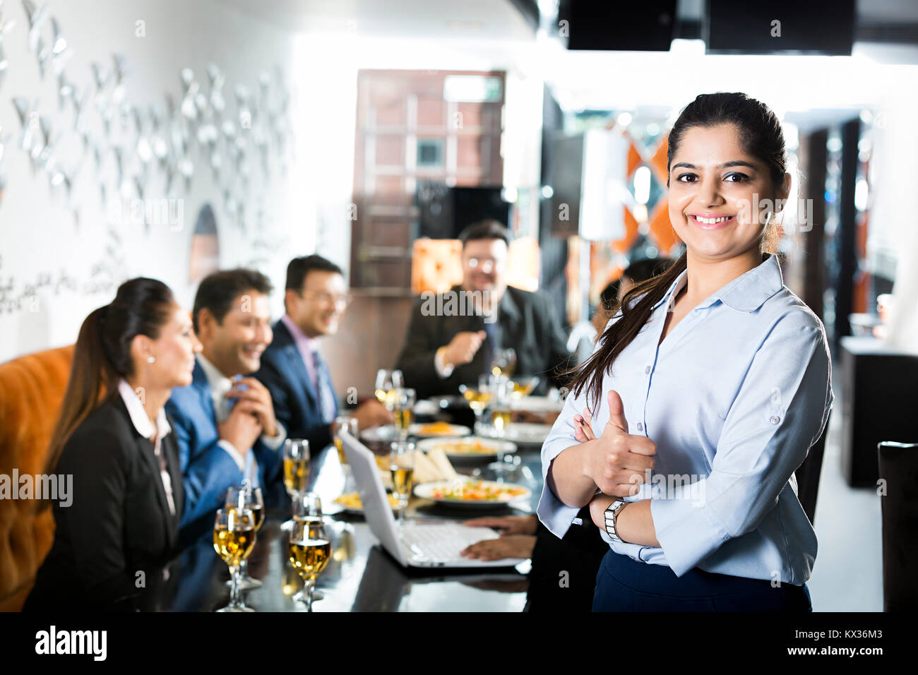 Imprenditrice che mostra pollice in su il successo con i colleghi nel ristorante - Party Foto Stock