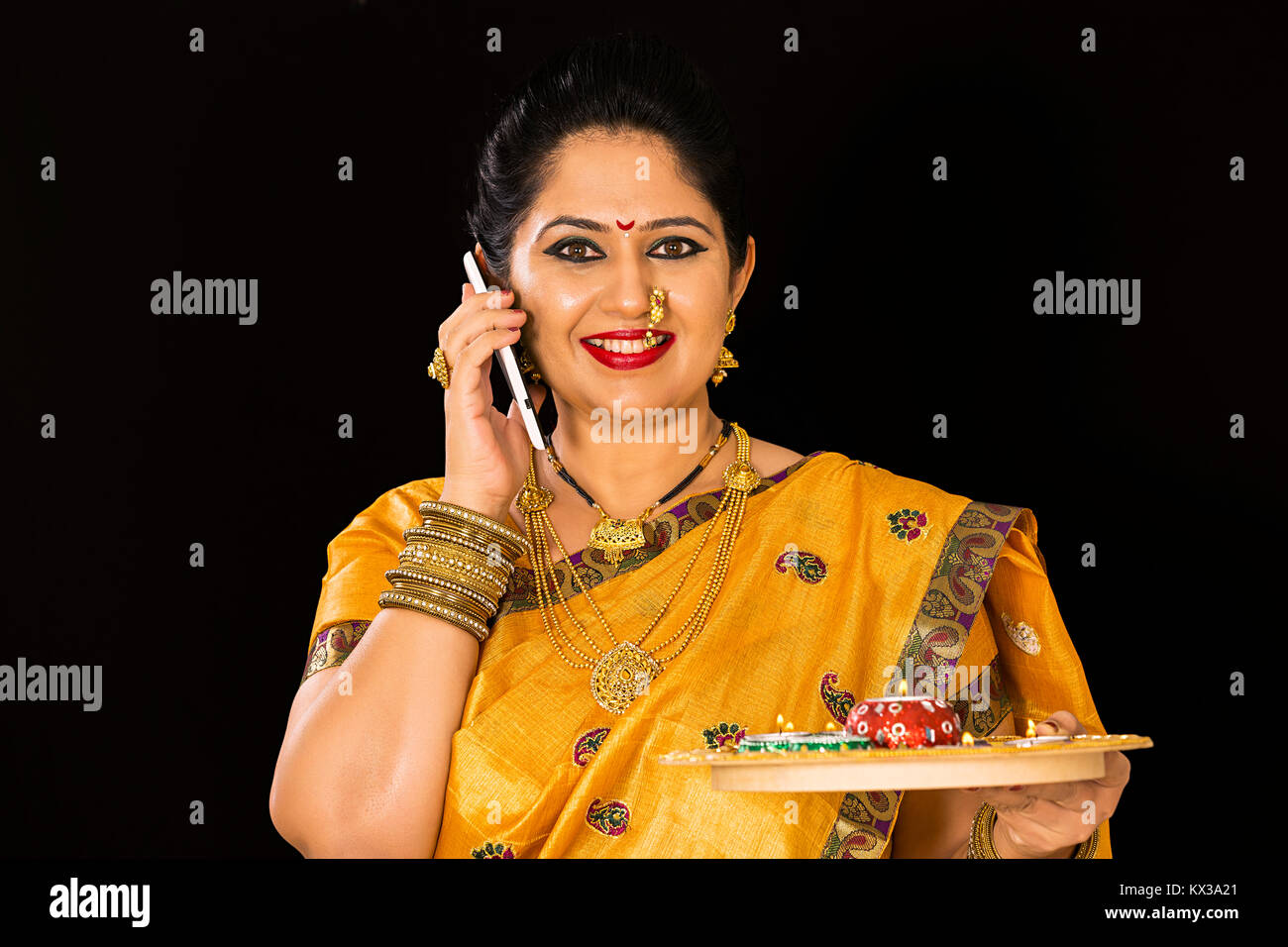 Indian Maharashtrian donna tenendo la piastra lampade a olio parlando Mobile Foto Stock