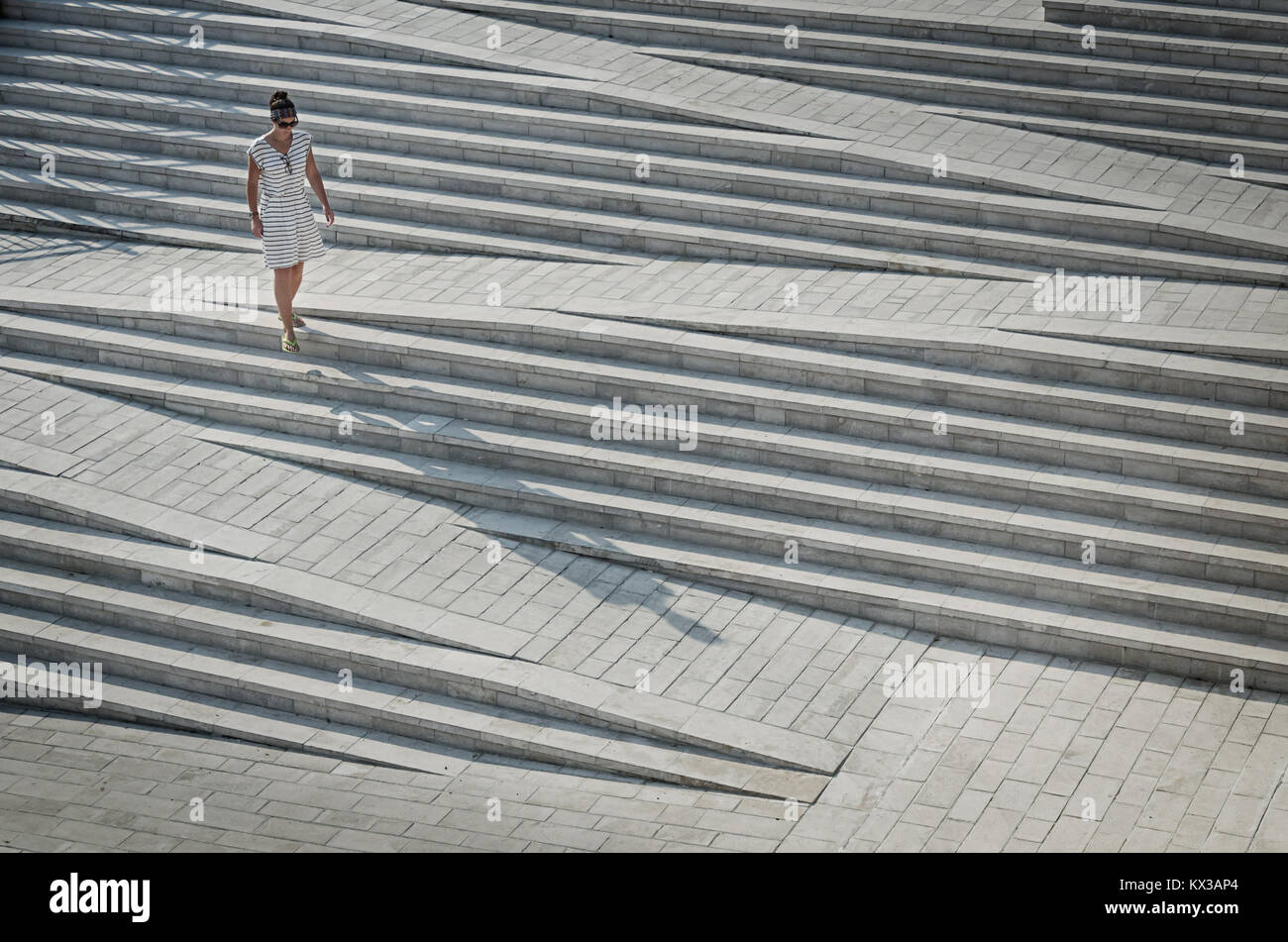 Donna in abito striata passeggiando per le operazioni Foto Stock