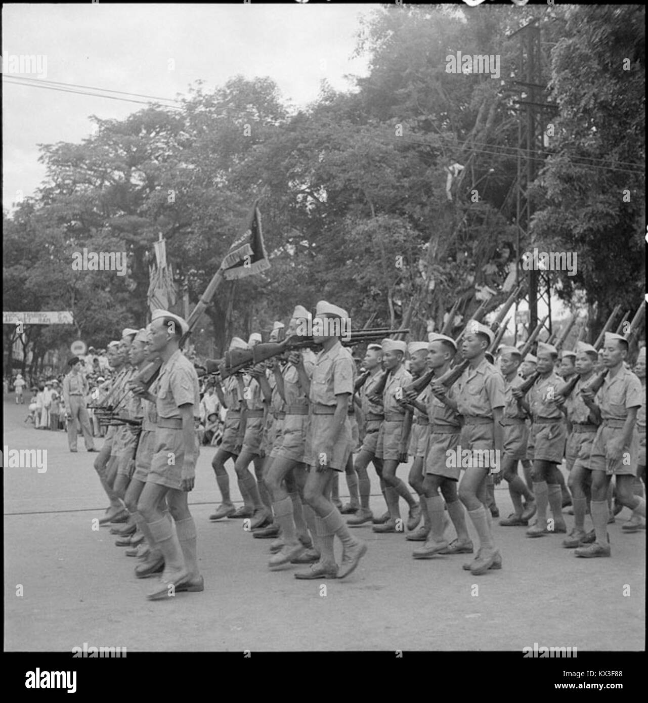 Questa fotografia cattura una parata militare ad Hanoi il 14 luglio 1951, con un battaglione dell'esercito nazionale vietnamita, che riflette la cultura militare del Vietnam nei primi anni '1950 Foto Stock