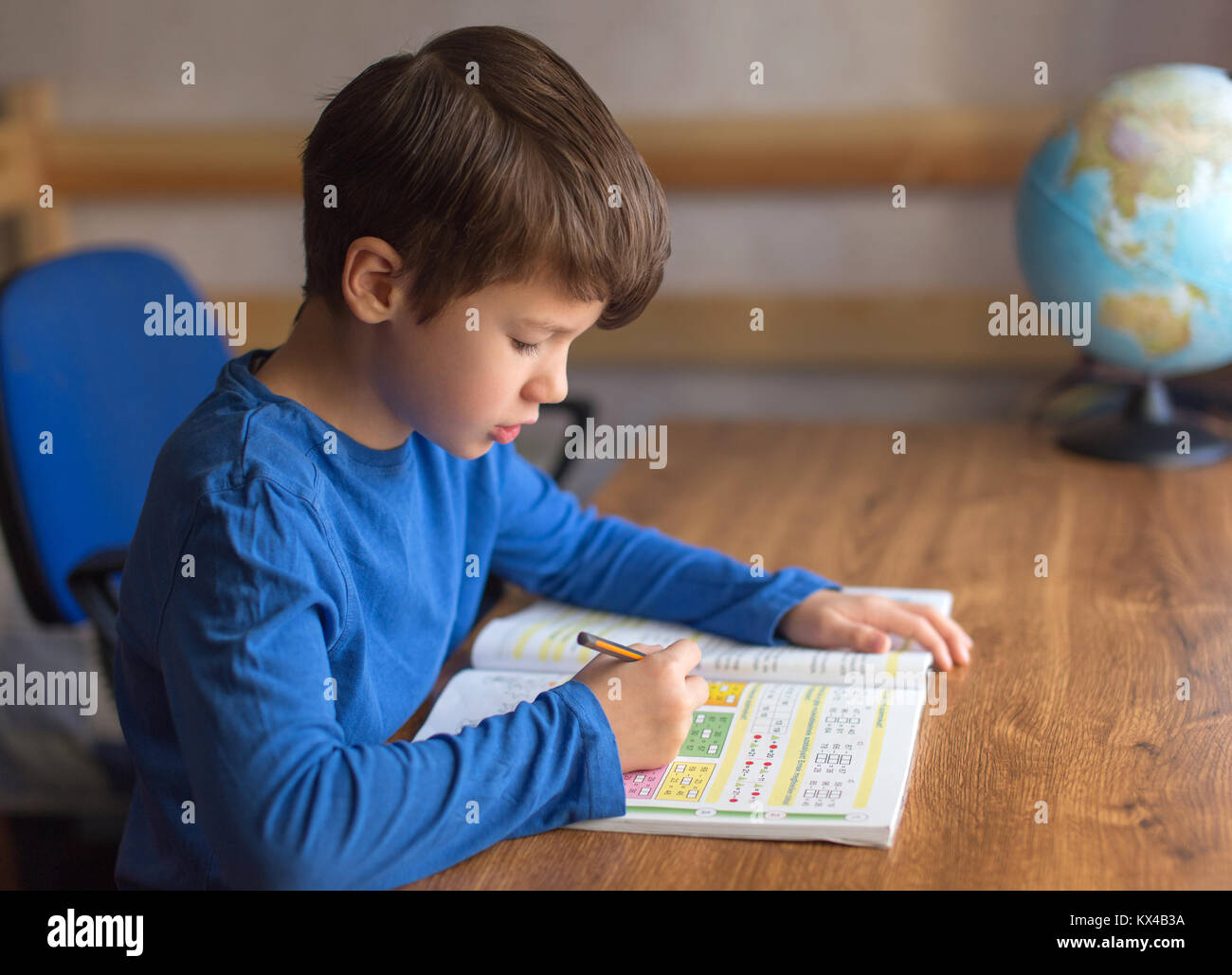 Little Boy risolvere esempi di matematica nel quaderno, compiti Foto Stock