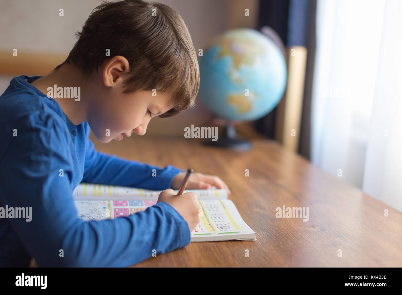 Poco intelligente schoolboy risolvere esempi di matematica nel quaderno, compiti Foto Stock