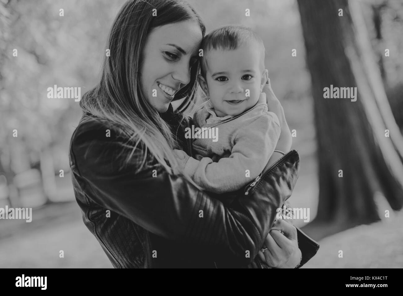 Giovane madre e bambino in autunno park a giornata di sole Foto Stock