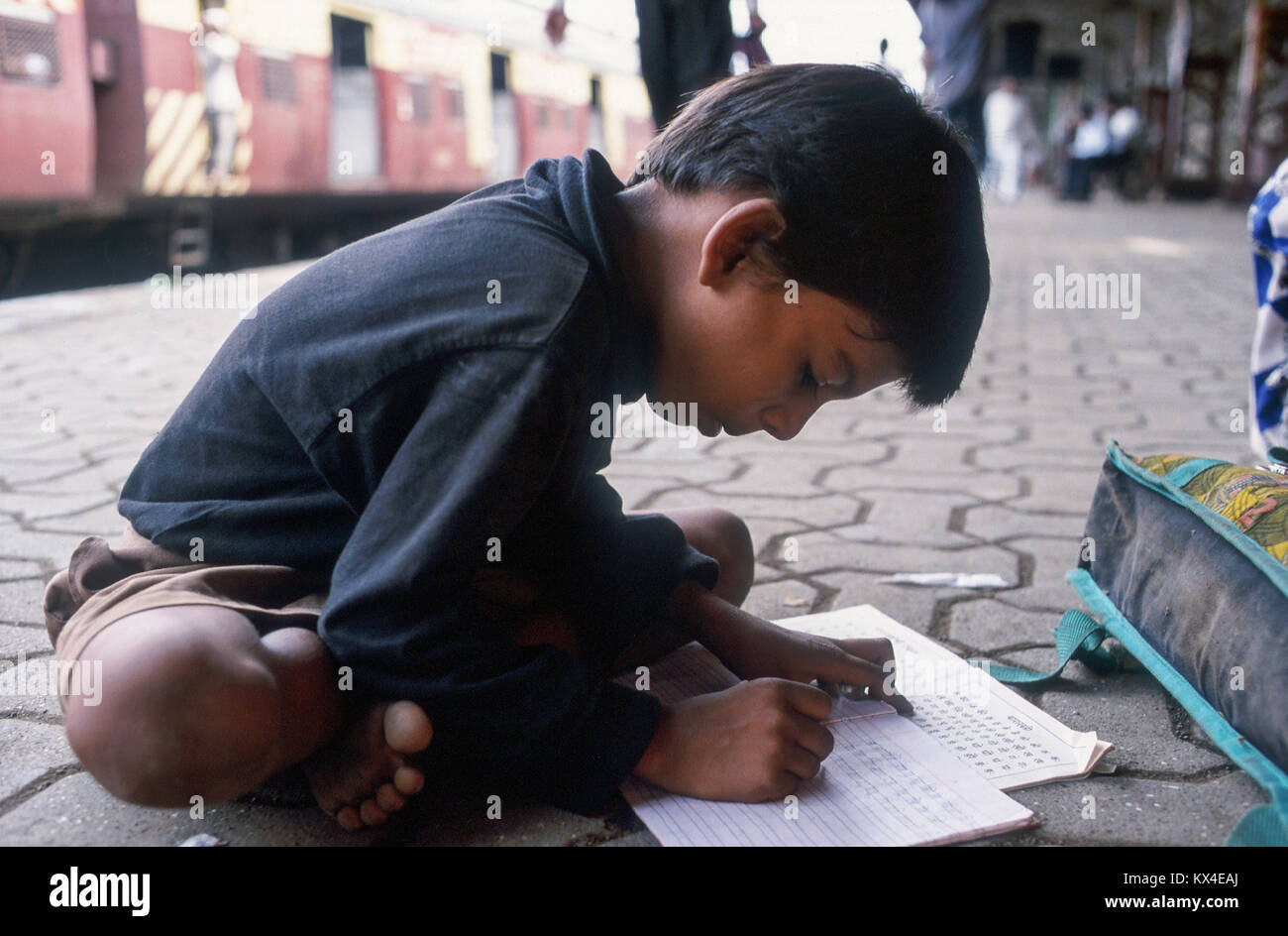 INDIA, Mumbai (ex Bombay, la voce delle ONG dà istruzione classi per strada e ferrovia bambini sulla piattaforma a Andheri stazione ferroviaria, ragazzo Raju, dietro il treno cittadino di western railway Foto Stock