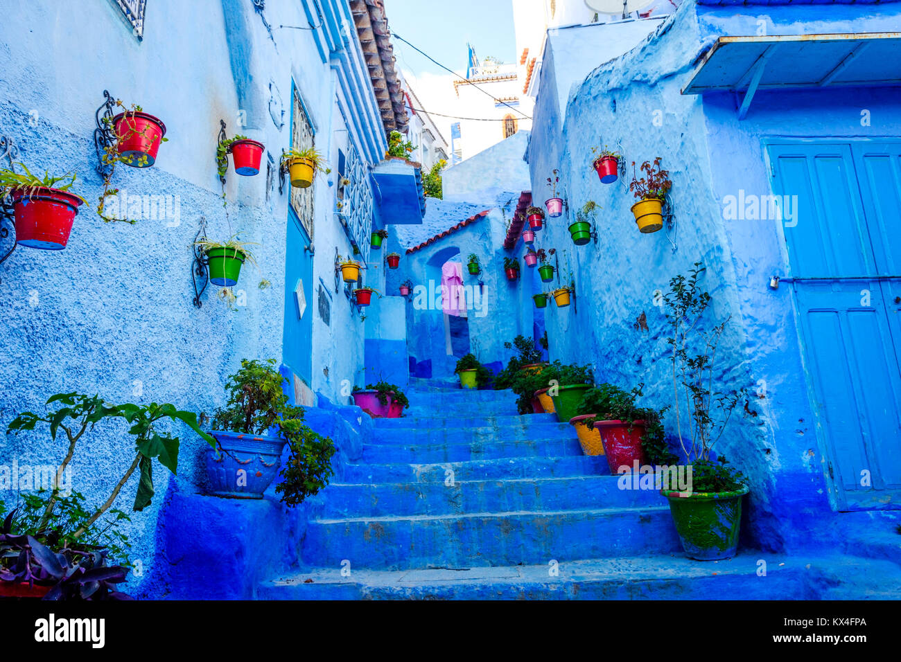 Strada blu con fiori colorati in cestelli a Chefchaouen, Marocco Foto Stock