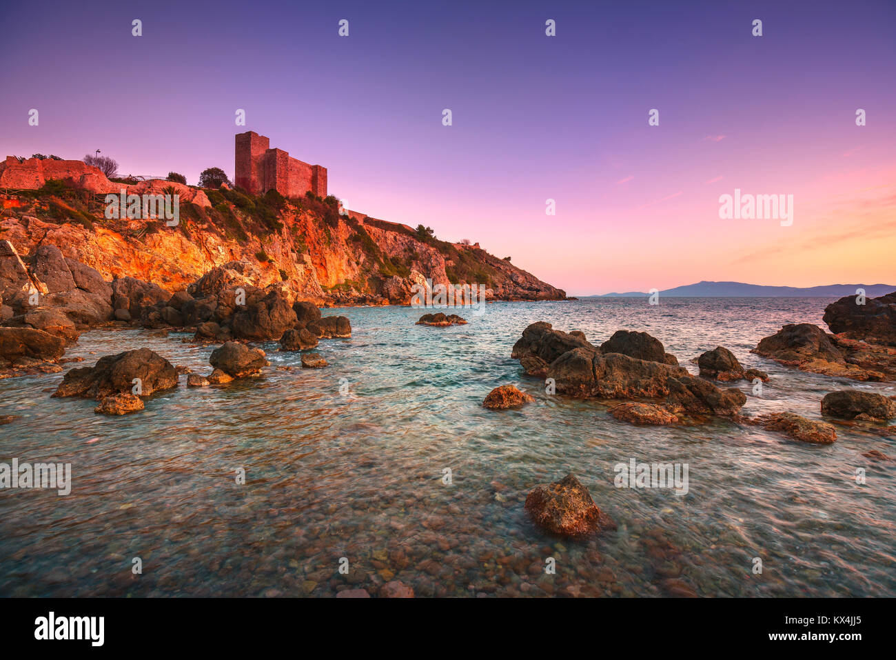 Talamone la spiaggia di roccia e fortezza medievale Rocca Aldobrandesca pareti e al tramonto. Maremma Argentario italiano destinazione di viaggio. Toscana, Italia. Foto Stock