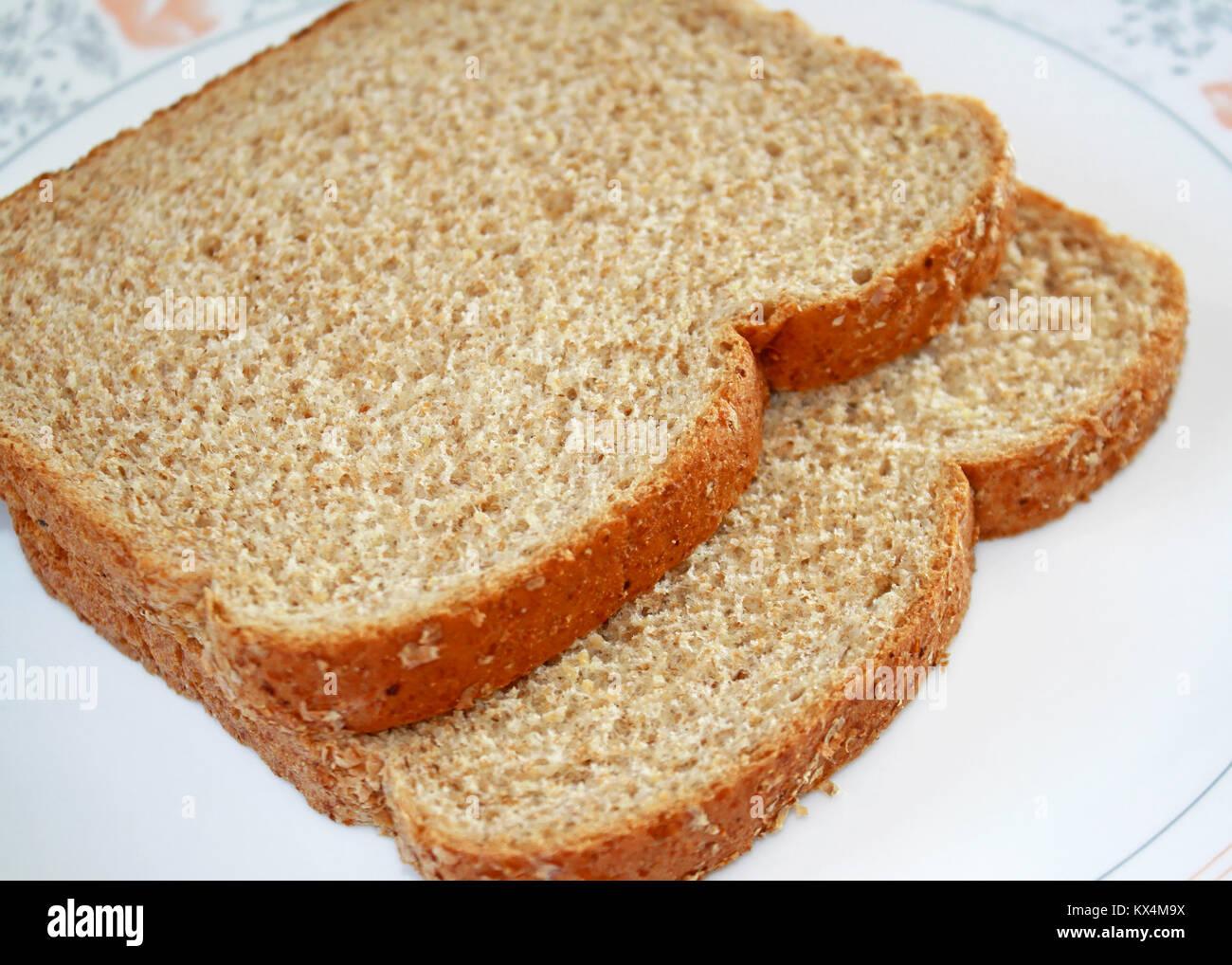 Due fette di nutriente fresco tutto il pane di grano isolato su piastra bianca Foto Stock