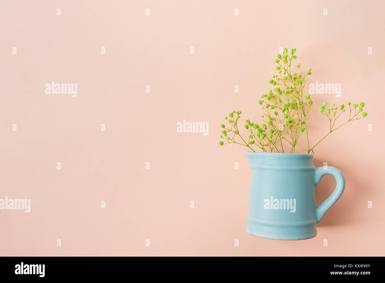 Piccolo bouquet di giallo dei fiori di acacia in ceramica Vintage brocca blu su sfondo rosa. Piatti creativi laici. Sito Web Modello di pagina di intestazione. Spazio copia Pasqua M Foto Stock