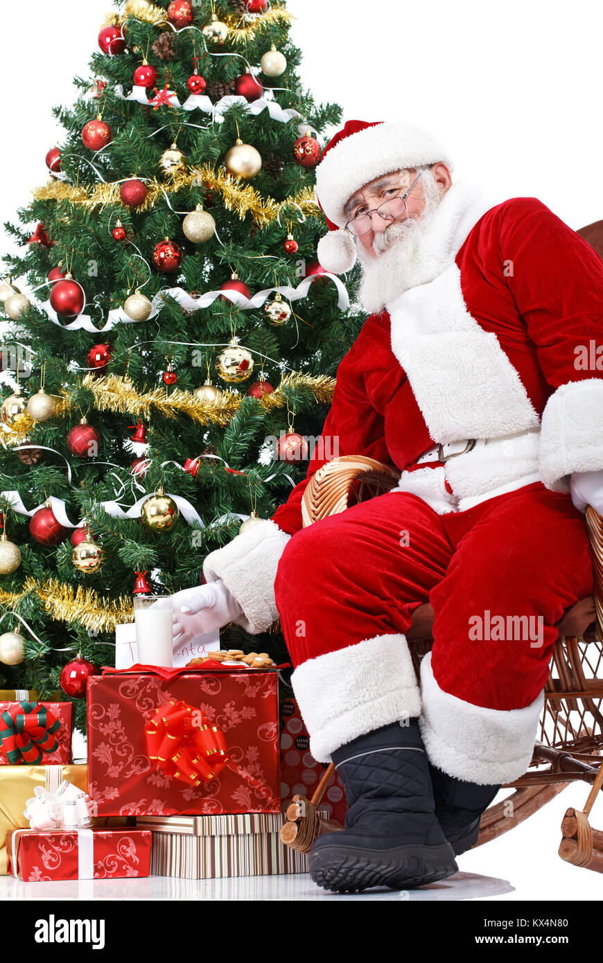 Santa seduta accanto ad albero di Natale e tenendo il latte , che sono stati lasciati per lui Foto Stock