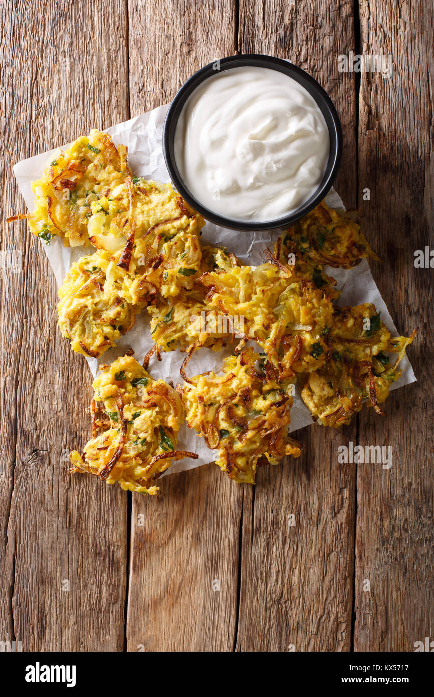 In casa fritto indiano onion bhaji con yogurt vicino sul tavolo. verticale in alto vista da sopra Foto Stock