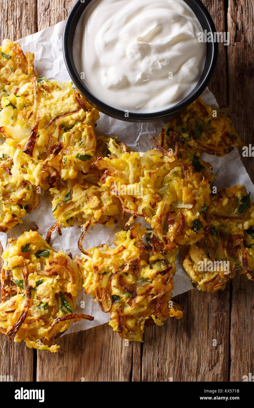 Cipolla croccante Bhajis vegane snack o del motorino di avviamento con yogurt close-up. verticale in alto vista da sopra Foto Stock