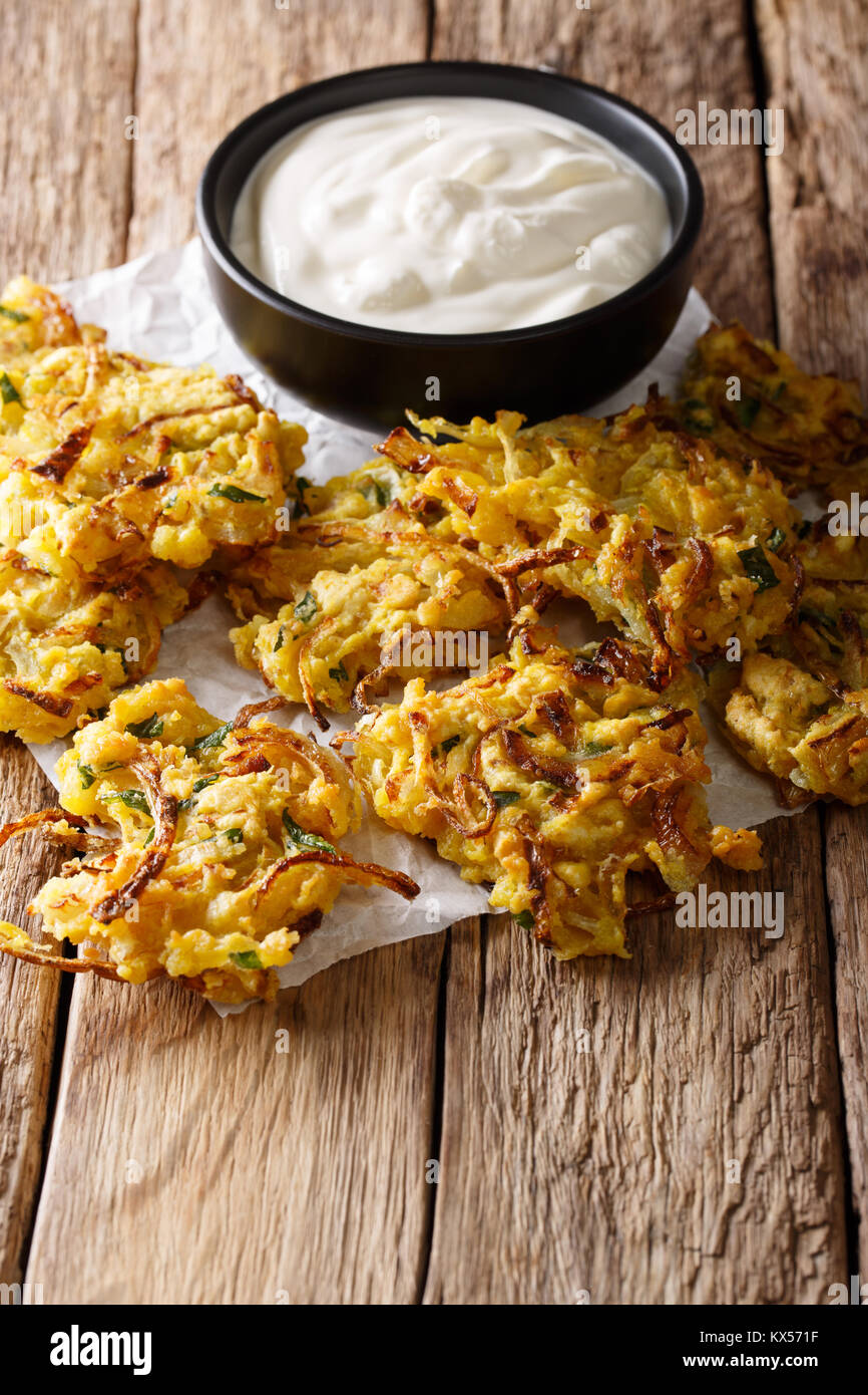 Cipolla croccante Bhajis vegane snack o del motorino di avviamento con yogurt vicino sul tavolo. In verticale Foto Stock