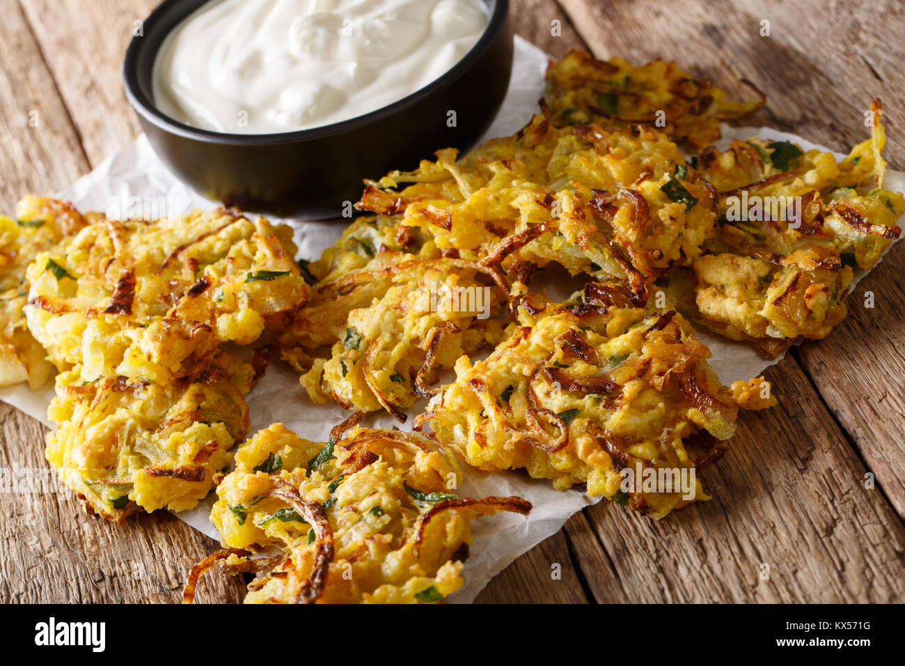 Snack croccante di cipolla fritti con yogurt vicino sul tavolo orizzontale. Foto Stock